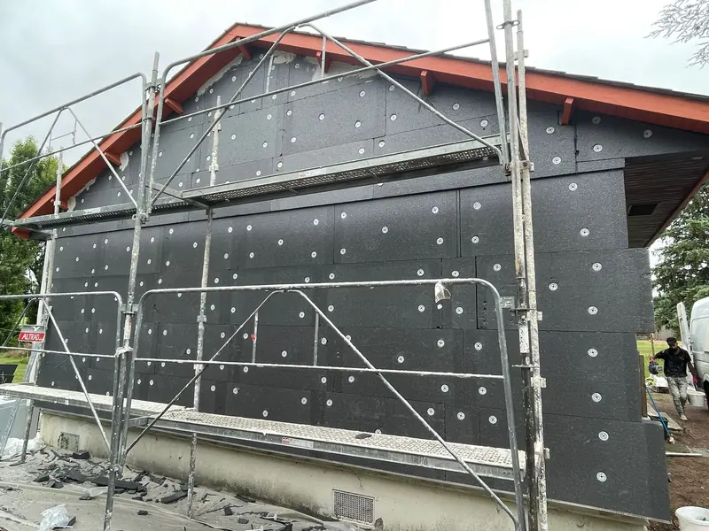 Pose de panneaux isolants sur une maison, chantier d’isolation par l’extérieur